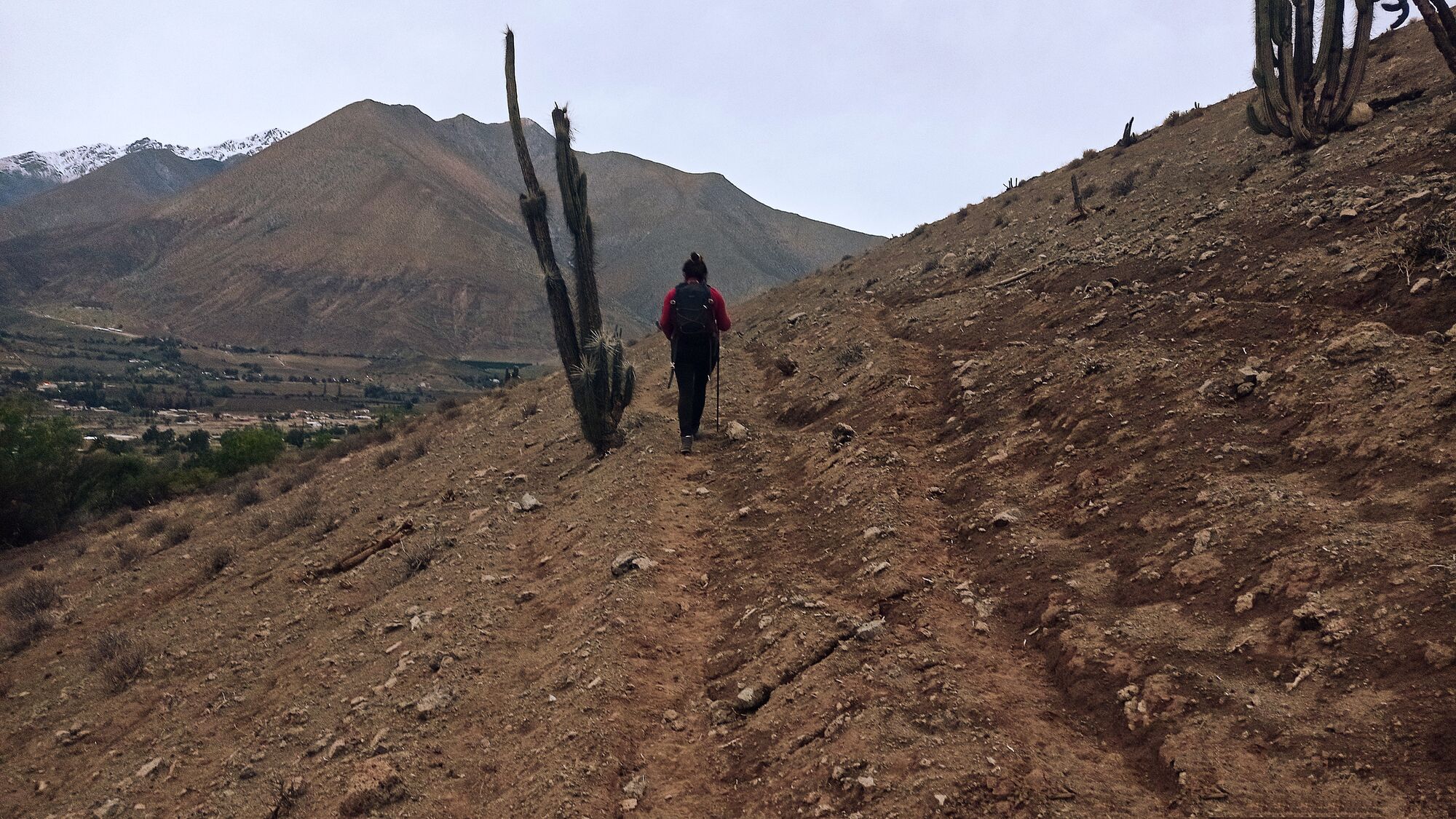 A guest walking a gentle trail through the mountains, the village and valley floor spread out below